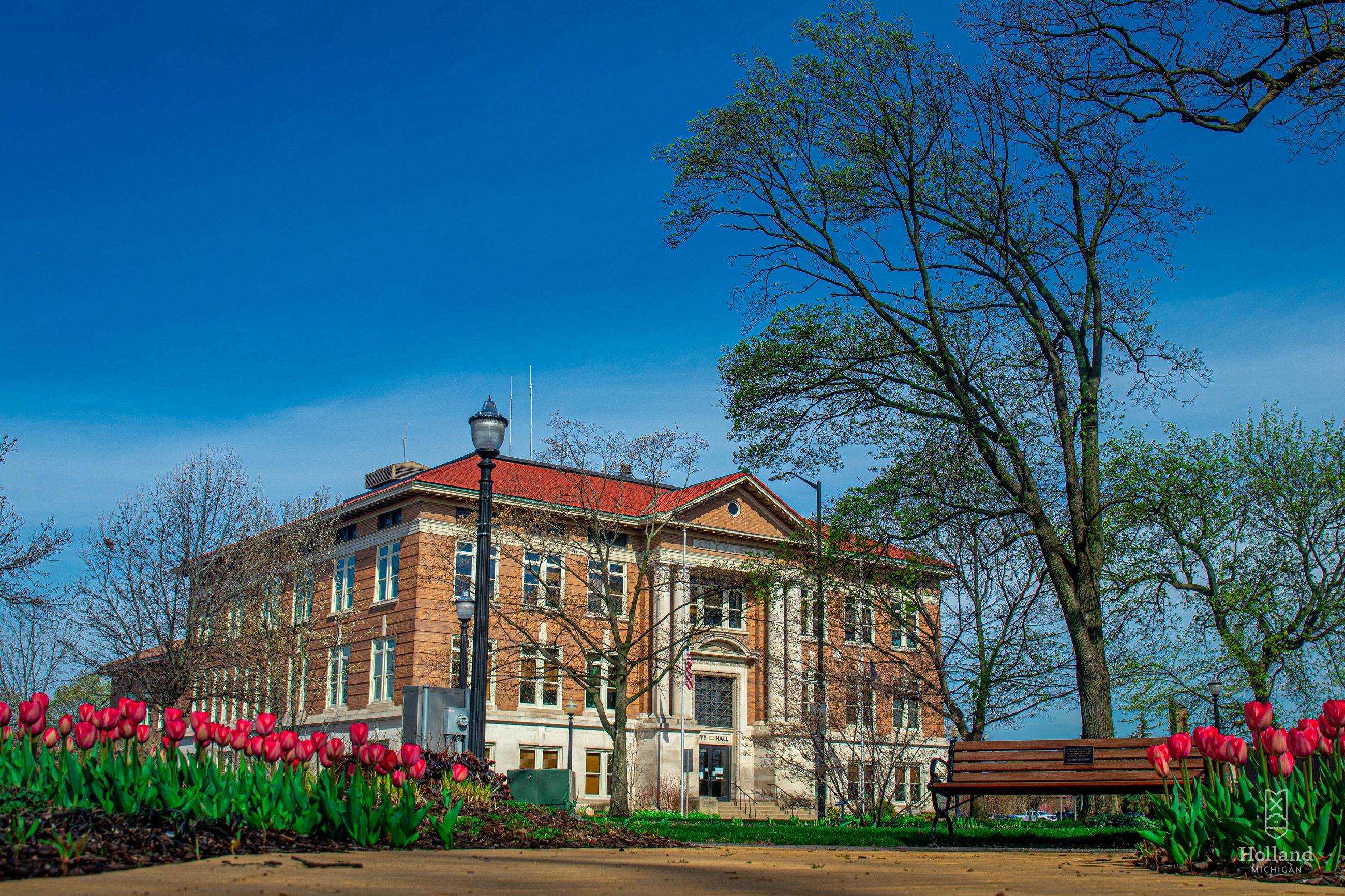 Exterior photo of Holland City Hall with pink tulips in the foreground