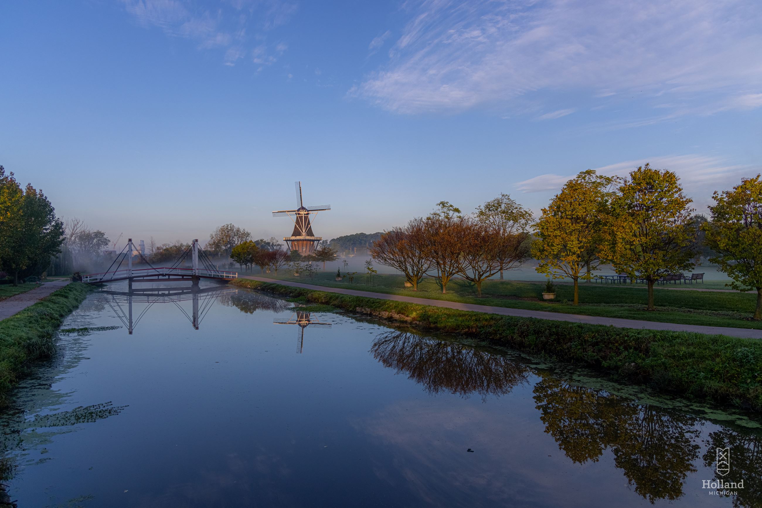 calm water with large windmill in the background against a deep blue sky