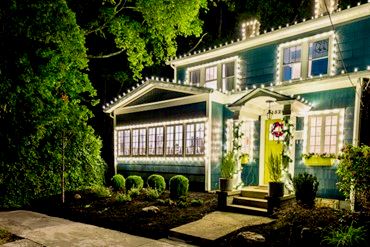 front of 2-story with windows across the front, decorated with white holiday lights 