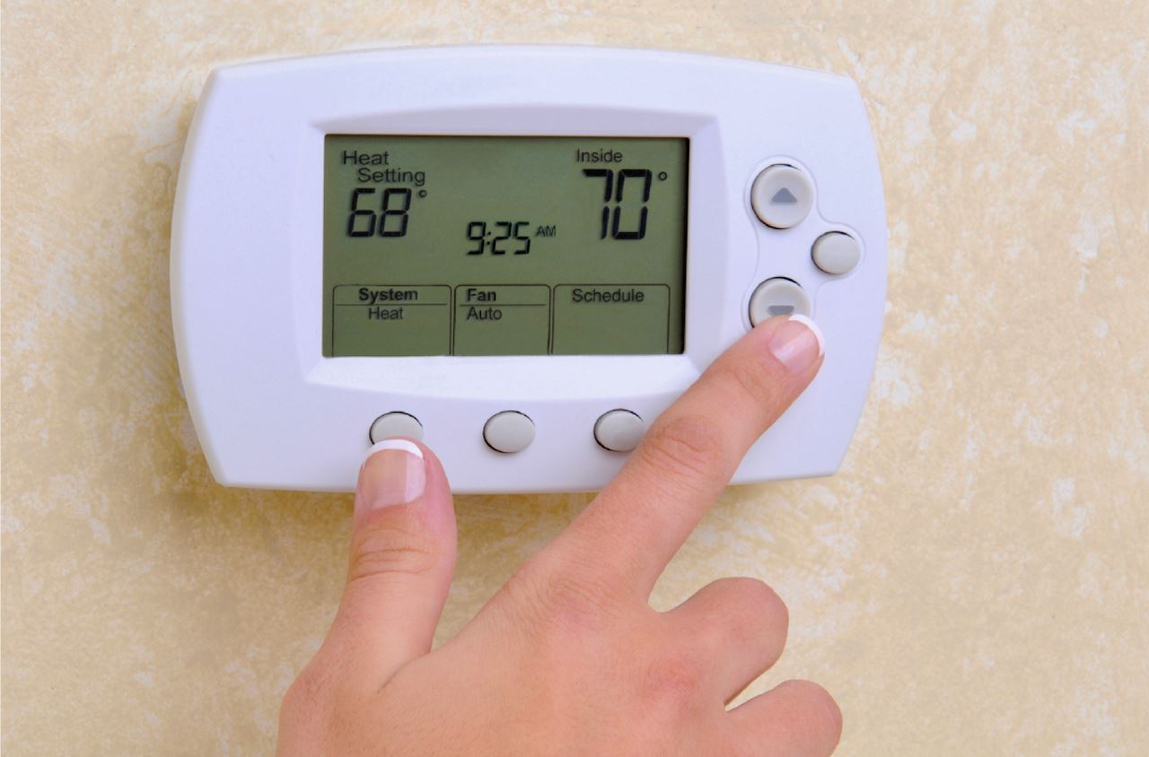 Home Interior Thermostat with person's hands on the controls