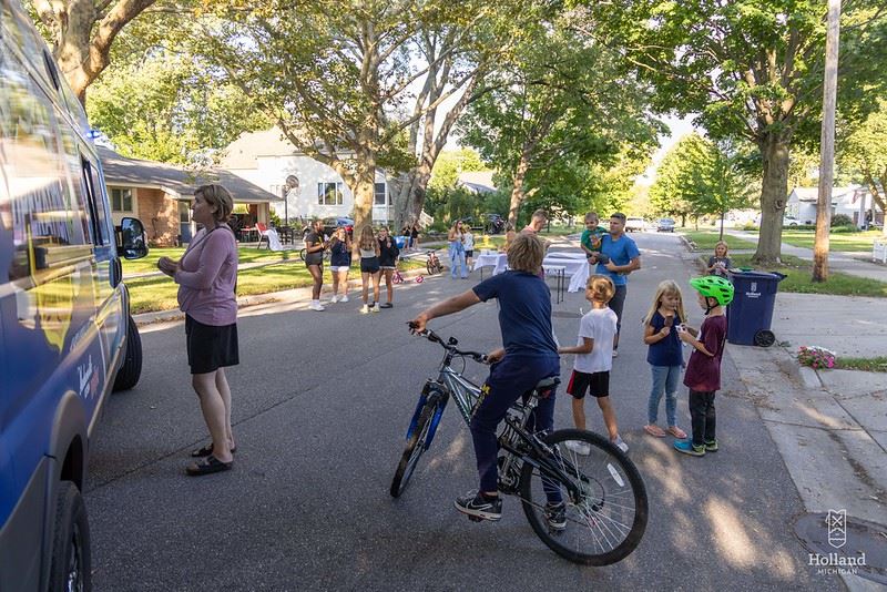 Neighbors connecting on the street enjoying food and ice cream during a block party.