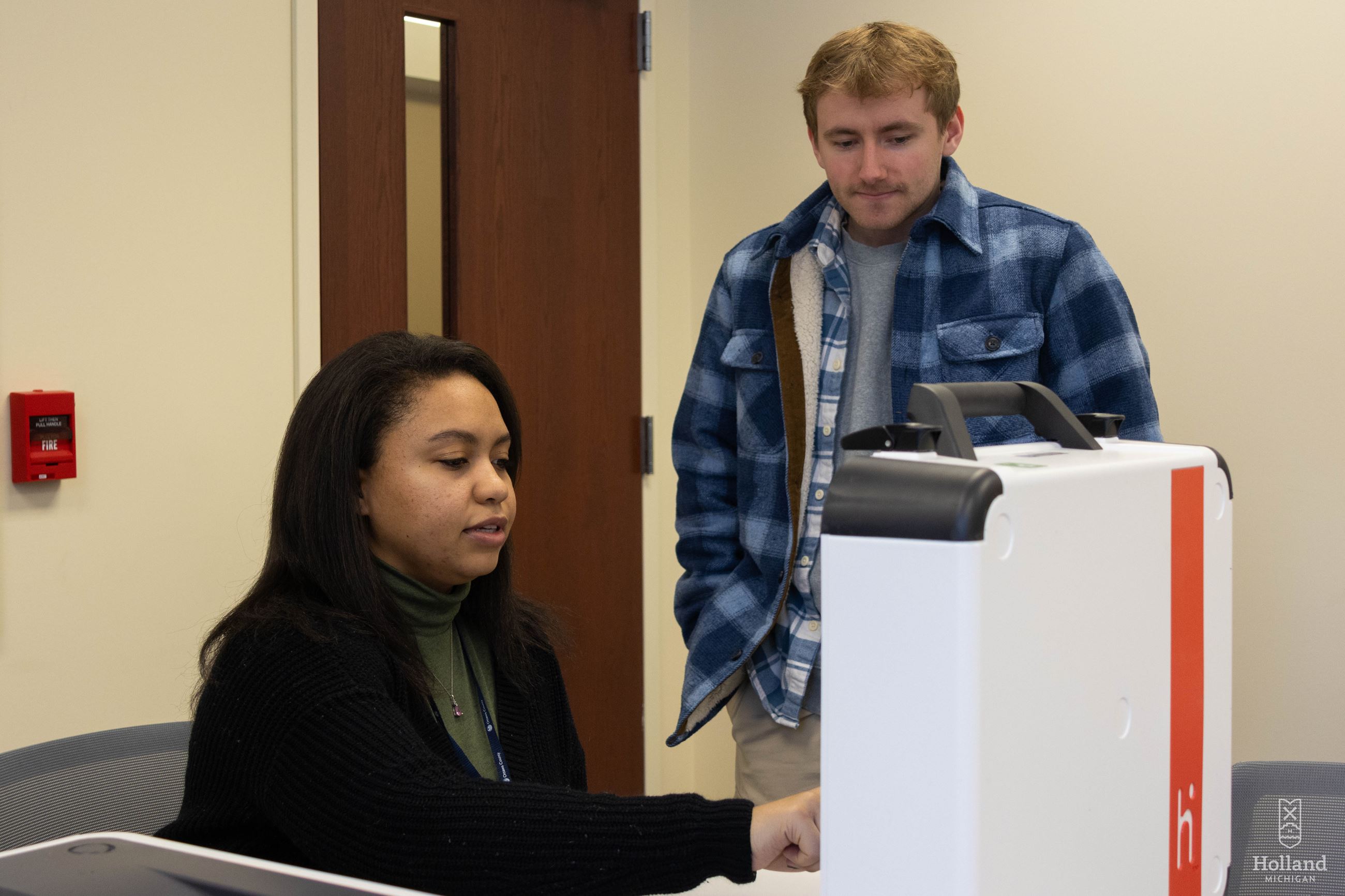 Election worker looking up a voter's address on a machine. Man standing to the side w