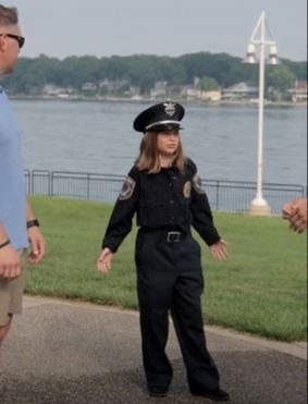 Young girl dressed in police uniform talking to two people about firework safety