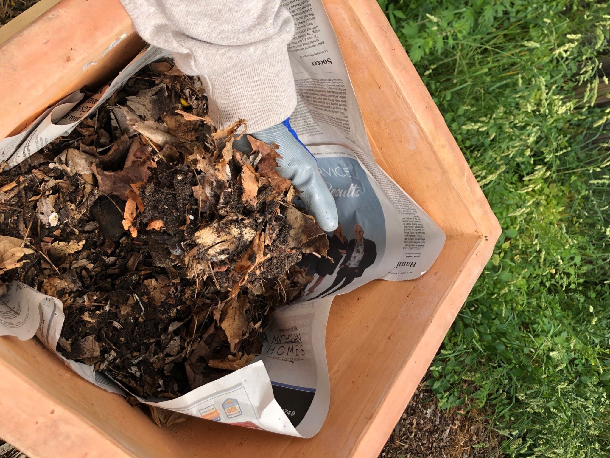 close up of gloved hands holding a yard compost pile