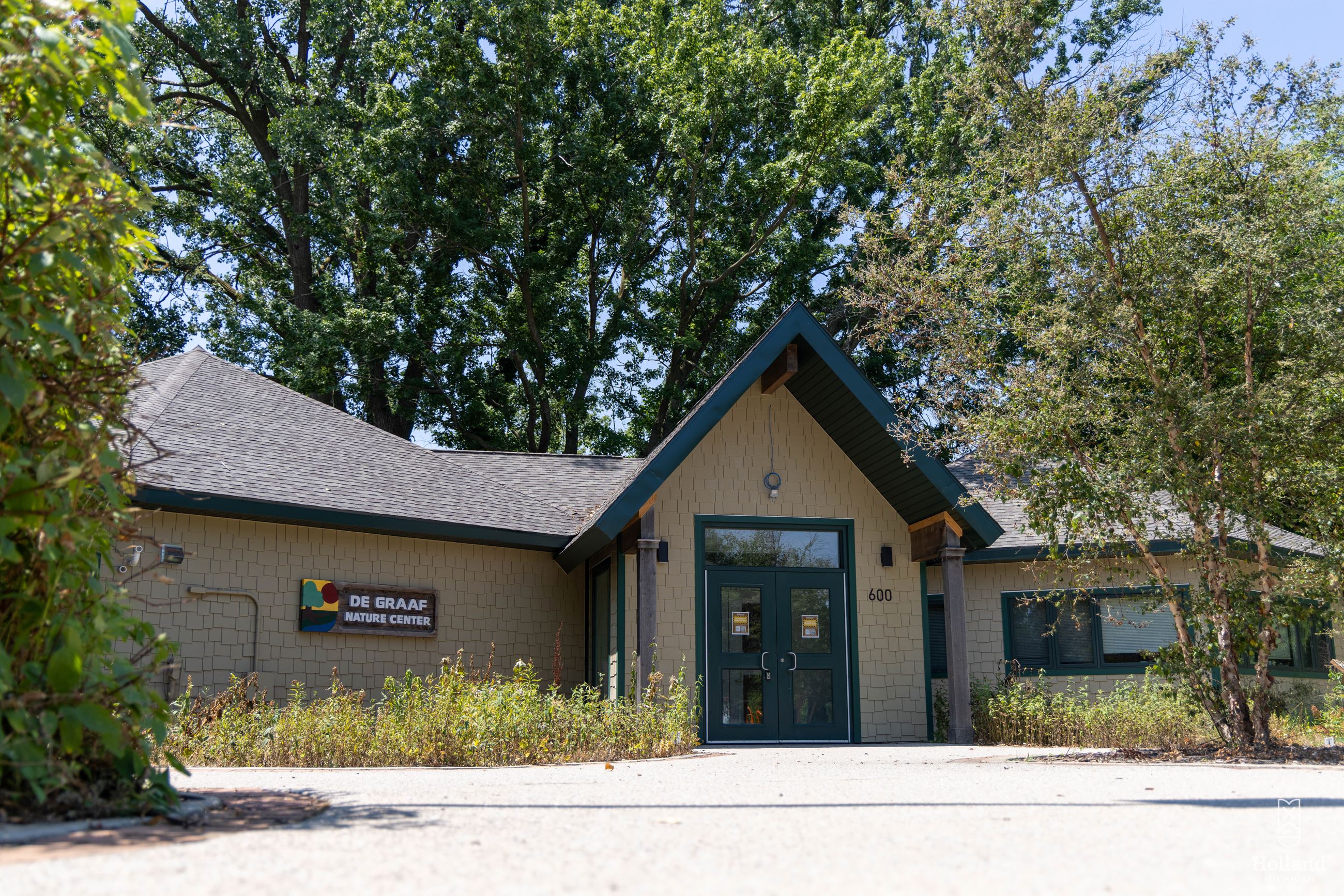 Nature Center building with pitched roof in the center, green brush on sides of building
