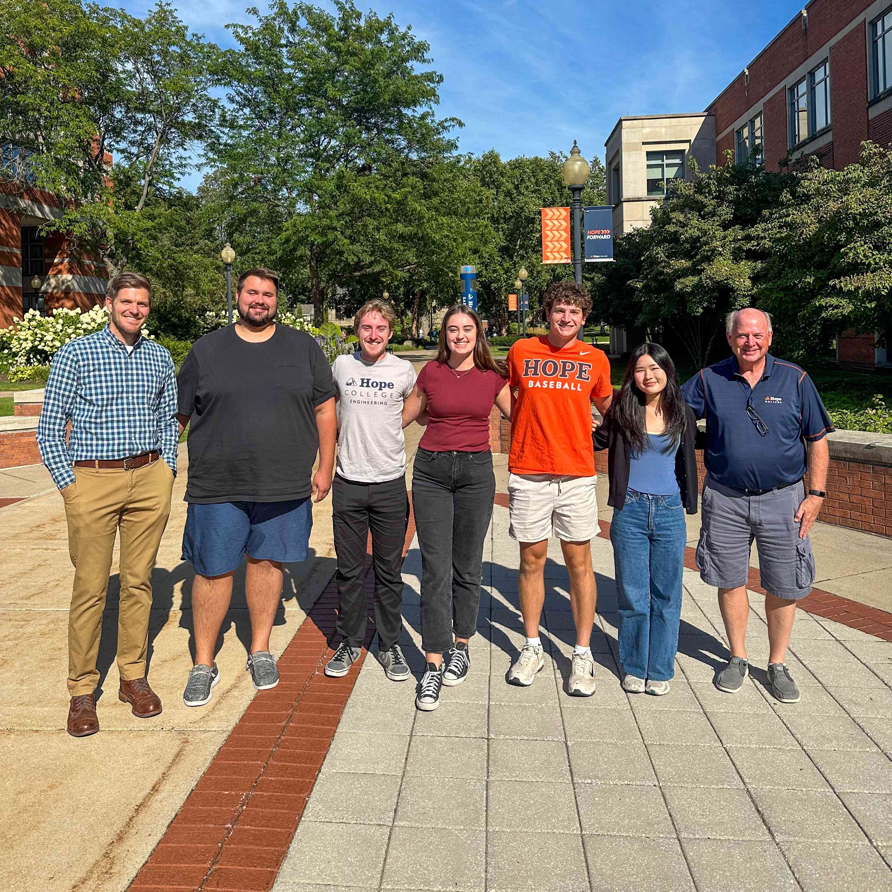 Group of college students in a line standing outside and smiling