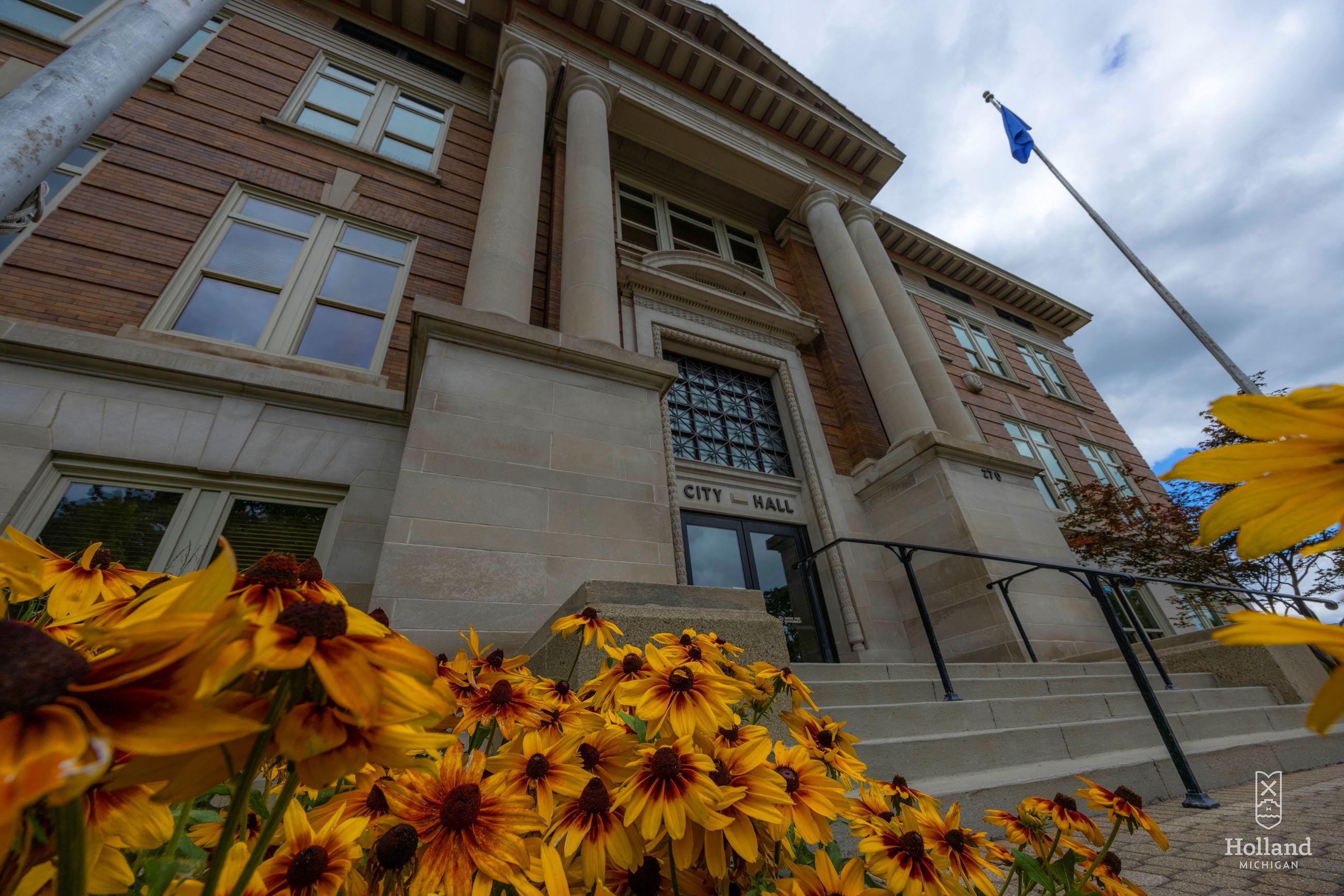 brick and stone 4 story building in the background with yellow and brown flowers  in corner 
