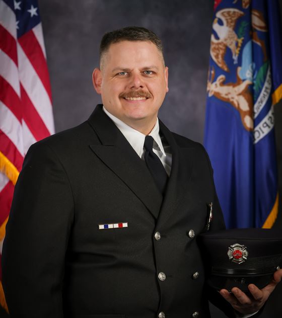 Professional portrait of a male firefighter in dress uniform holding his hat