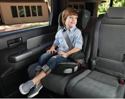 Child sitting in a car seat that is facing the front of the car, in the back seat of the car