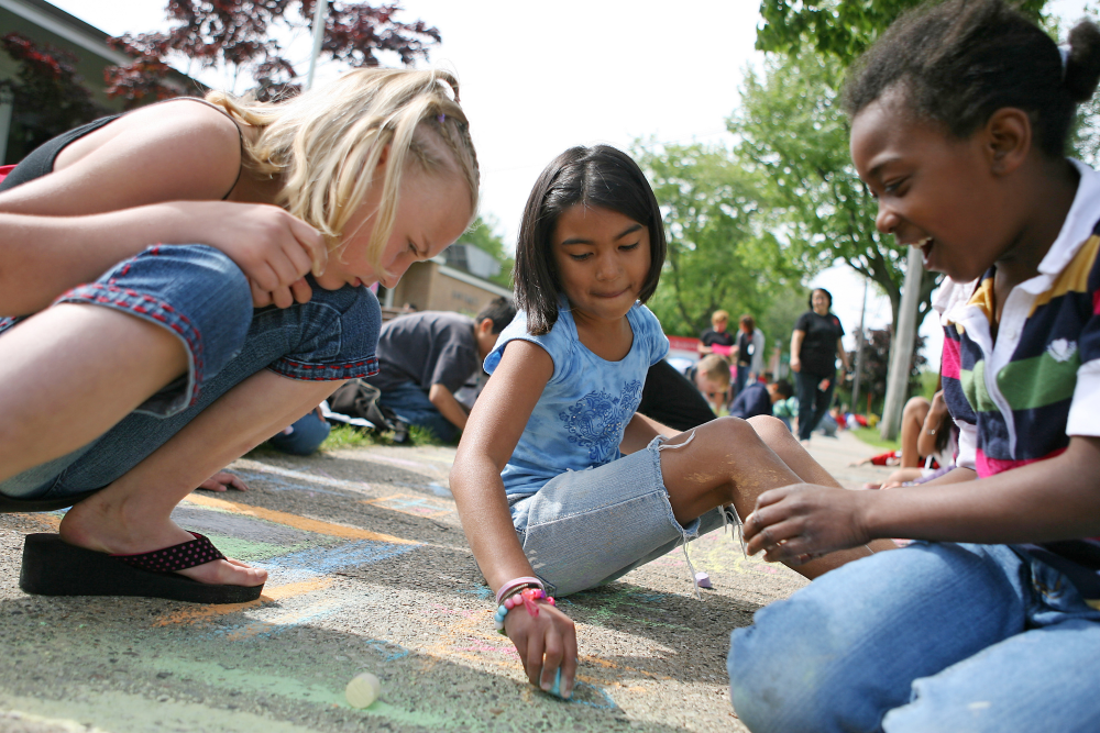 Young children making art with sidewalk chalk